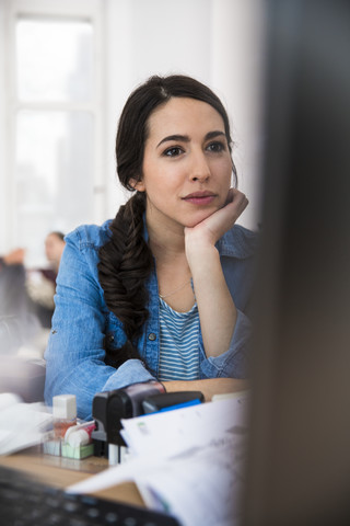 Frau am Schreibtisch mit Blick auf den Computerbildschirm, lizenzfreies Stockfoto