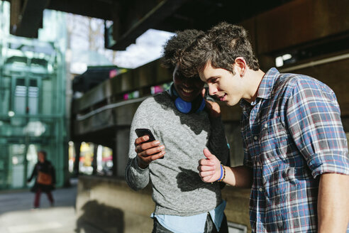 UK, London, zwei beste Freunde schauen etwas auf dem Smartphone - BOYF000122