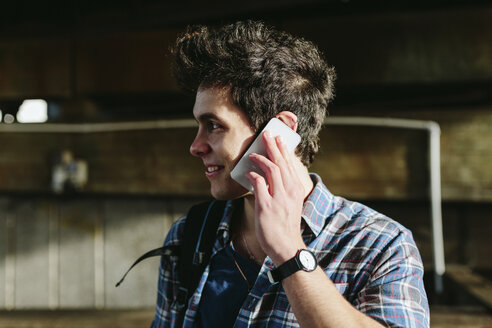 Lächelnder junger Mann beim Telefonieren mit Smartphone - BOYF000125