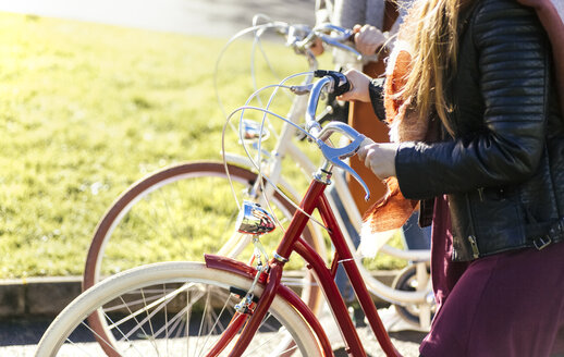 Two young women strolling with bicycles - MGOF001477