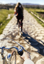 Zwei junge Frauen fahren mit dem Fahrrad einen Weg entlang - MGOF001506