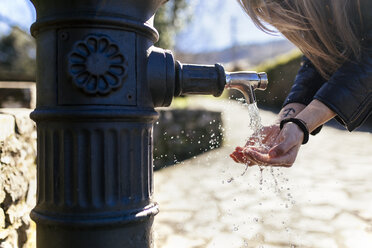 Junge Frau beim Händewaschen an einem Brunnen - MGOF001514