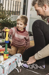 Father and son playing with building bricks in front of Christmas tree - MFF002761