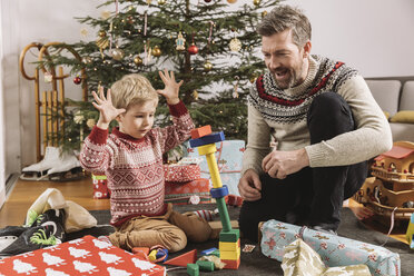 Father and son playing with building bricks in front of Christmas tree - MFF002762