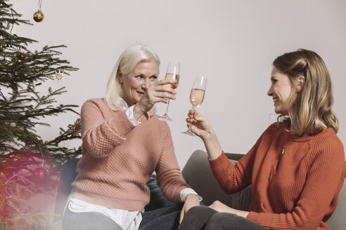 Ältere Frau und jüngere Frau stoßen mit Gläsern am Weihnachtsbaum an - MFF002765