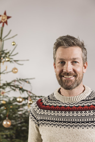 Porträt eines Mannes vor einem Weihnachtsbaum, lizenzfreies Stockfoto