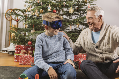 Glücklicher Großvater betrachtet die neue Skibrille seines Enkels vor dem Weihnachtsbaum - MFF002772