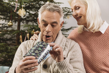 Älteres Paar tauscht Weihnachtsgeschenke vor dem Baum aus - MFF002775