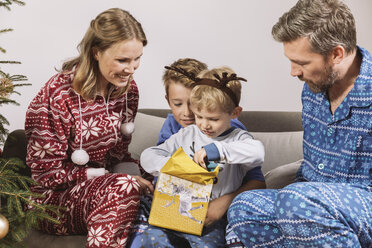 Eltern beobachten ihren Sohn beim Auspacken eines Weihnachtsgeschenks - MFF002784