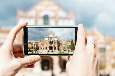 Spain, Barcelona, man taking picture of Sant Pau Art Nouveau Site with smartphone, close-up - GEMF000777