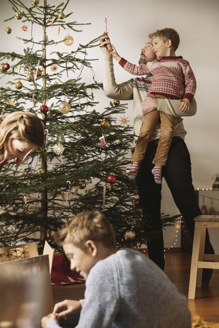 Familie beim Schmücken des Weihnachtsbaums, lizenzfreies Stockfoto