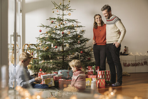 Glückliche Eltern, die ihren Kindern beim Auspacken der Weihnachtsgeschenke zusehen - MFF002810
