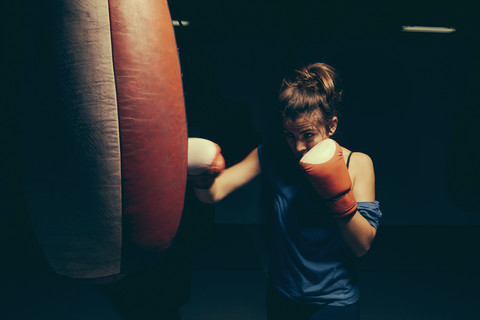 Female boxer exercising at punch bag stock photo