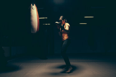 Female boxer exercising at punch bag - ZEDF000077