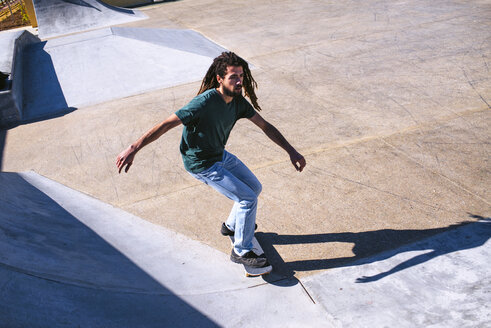 Junger Mann mit Dreadlocks auf dem Skateboard in einem Skatepark - KIJF000231