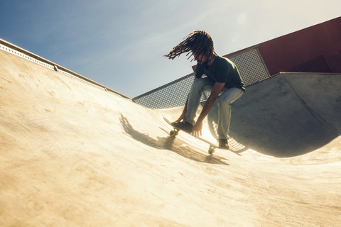 Junger Mann mit Dreadlocks auf dem Skateboard in einem Skatepark, lizenzfreies Stockfoto