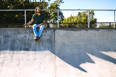 Junger Mann mit Dreadlocks sitzt in einem Skatepark - KIJF000237