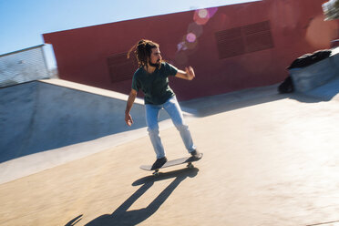 Young man with dreadlocks skateboarding in a skatepark - KIJF000238