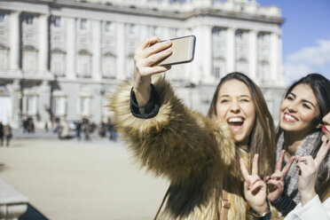 Spanien, Madrid, zwei glückliche Frauen machen ein Selfie mit Smartphone vor dem Königspalast - ABZF000263