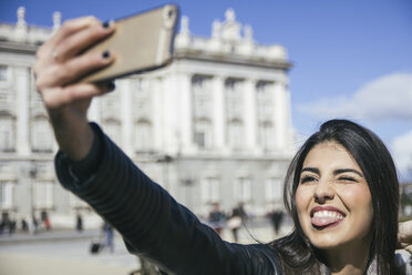 Spanien, Madrid, Porträt einer Frau, die Grimassen schneidet, während sie ein Selfie mit ihrem Smartphone macht - ABZF000269