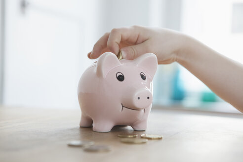 Little boy putting coin into piggy bank, close-up - RBF004234