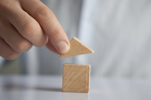 Man building up house with building blocks, close-up - RBF004235