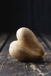 Heart-shaped potato on dark wood - CSF027251
