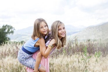 Spain, Girona, portrait of two happy sisters playing on a meadow - VABF000304