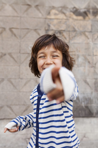 Porträt eines lachenden kleinen Jungen, der auf den Betrachter zeigt, lizenzfreies Stockfoto