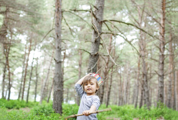 Porträt eines kleinen Jungen mit Holzstock und Papierkrone im Wald - VABF000333