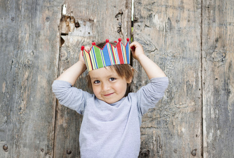 Porträt eines lächelnden kleinen Jungen mit Papierkrone, lizenzfreies Stockfoto