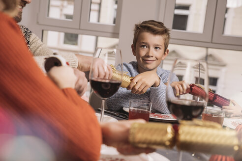 Junge zieht am Familientisch an den Enden von Weihnachtskrachern - MFF002833