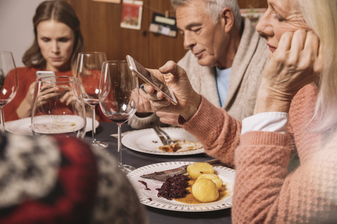 Familienmitglieder spielen nach dem Weihnachtsessen mit ihren Smartphones, lizenzfreies Stockfoto