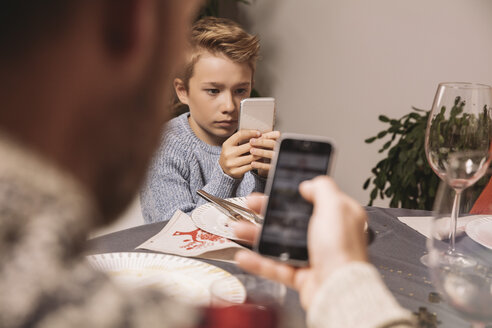 Junge spielt nach dem Weihnachtsessen mit seinem Smartphone - MFF002860