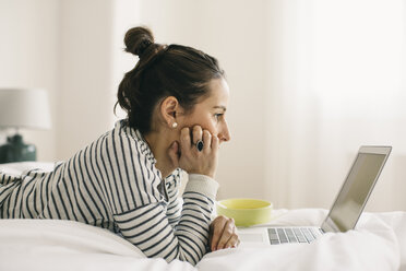 Relaxed woman lying in bed using laptop - EBSF001235