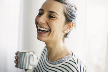 Lachende Frau mit einer Tasse Kaffee in der Hand - EBSF001243