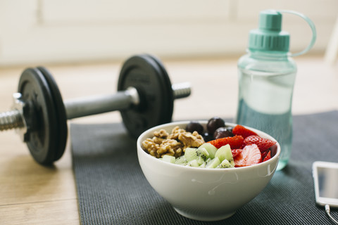 Dumbbell, drinking bottle, fruit bowl and smartphone stock photo