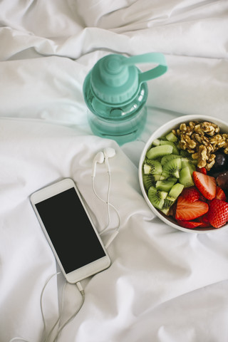Trinkflasche, Obstschale und Smartphone mit Kopfhörern auf der Decke, lizenzfreies Stockfoto