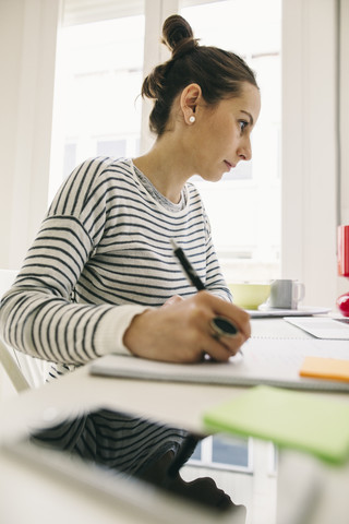 Woman at desk writing in notebook stock photo