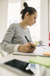 Woman at desk writing in notebook - EBSF001273