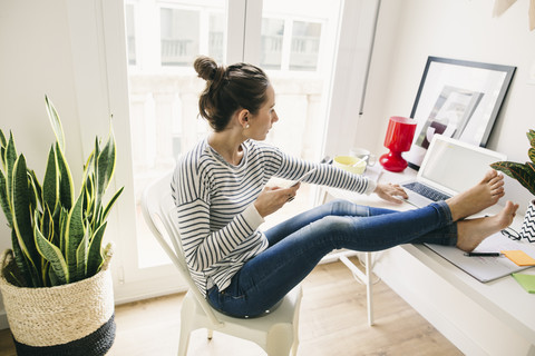 Woman at home laying feet on table using laptop stock photo