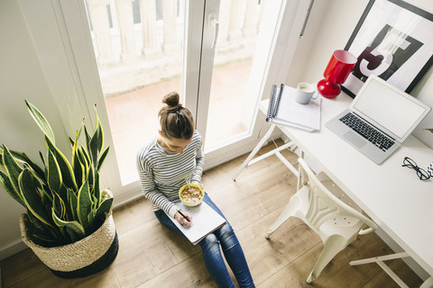 Woman sitting on floor writing on notepad stock photo