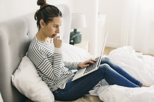 Frau sitzt im Bett und benutzt einen Laptop - EBSF001293