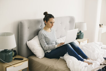 Frau sitzt im Bett und benutzt einen Laptop - EBSF001294