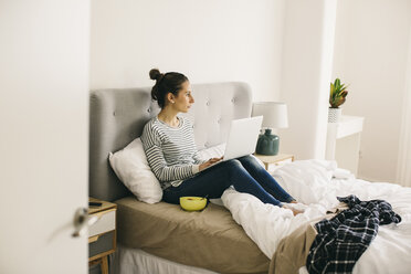 Frau sitzt im Bett und benutzt einen Laptop - EBSF001295