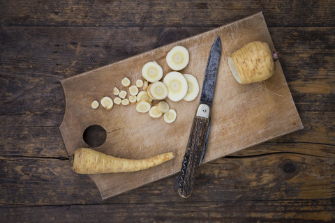 In Scheiben geschnittene Bio-Pastinaken und Taschenmesser auf Schneidebrett, lizenzfreies Stockfoto