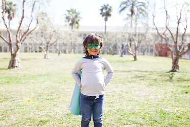 Portrait of grinning little boy dressed up as a superhero standing on a meadow - VABF000348