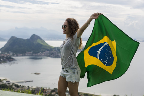 Brasilien, Frau mit brasilianischer Flagge auf einem Aussichtspunkt in Rio de Janeiro, lizenzfreies Stockfoto