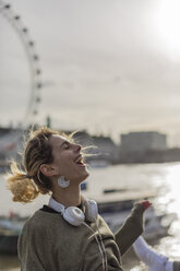 UK, London, laughing woman with headphones at River Thames - BOYF000151