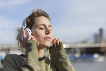 UK, London, Frau hört Musik an der Themse - BOYF000153